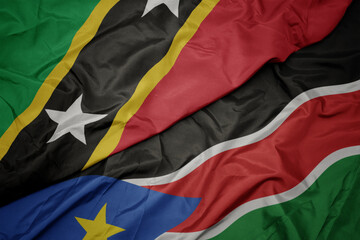 waving colorful flag of south sudan and national flag of saint kitts and nevis.