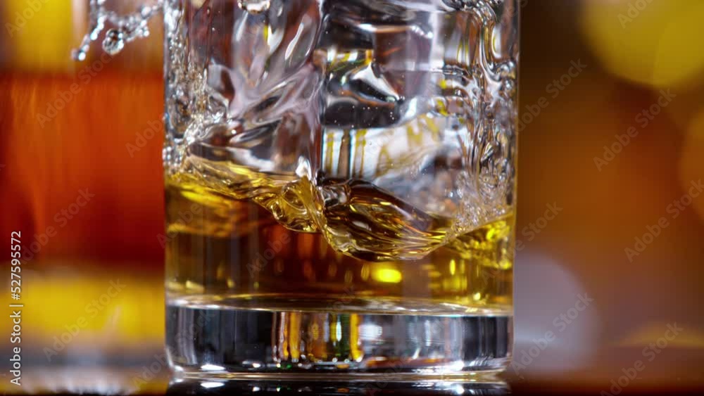 Poster super slow motion of falling ice cube into whiskey drink, camera motion. speed ramp effect. filmed o