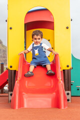 Baby playing in a playground having fun in summer, park adapted for small children from one to three years old