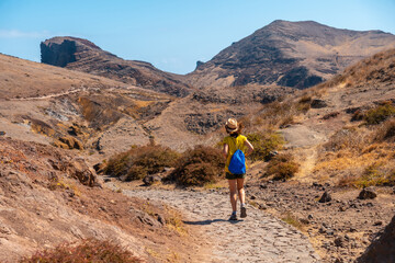 Obraz premium Young woman tourist on a trekking trail in Ponta de Sao Lourenco in summer, Madeira coast