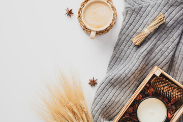 Fototapeta na wymiar Flat lay knitted scarf, autumn decorations, cup of coffee, wheat on white table. Cozy home desk table top view. Hygge style.