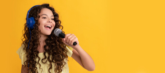 cheerful teen girl listen music in headphones and singing in microphone, vocal school. Child portrait with headphones, horizontal poster. Girl listening to music, banner with copy space.