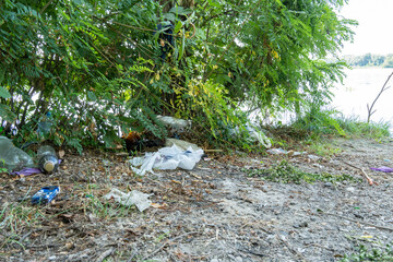Garbage dump in forest scattered on grass. Plastic trash in the woods after picnic. People illegally throw rubbish. World ecology problem of environmental protection. Garbage heap in nature.