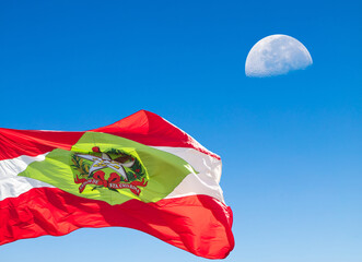 Flag of Santa Catarina in Brazil and moon in blue sky.