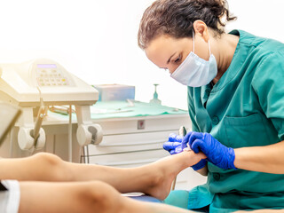 Female podiatrist doing chiropody in her podiatry clinic. Selective focus
