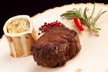 Steak on a wooden plate. On a dark background.
