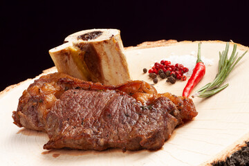 Steak on a wooden plate. On a dark background.