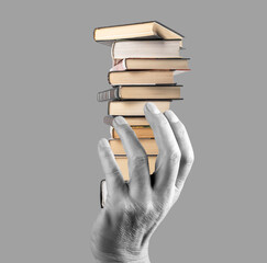 Hand holding books stack on grey background. Knowledge, intellectual development, wisdom,...