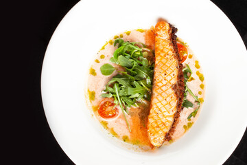 Grilled salmon steak in a bowl. On a dark background.