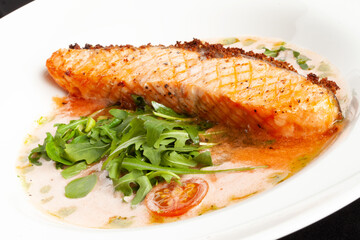 Grilled salmon steak in a bowl. On a dark background.