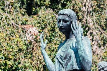 Fototapeta na wymiar La statua bronzea di una donna dolente su una tomba del cimitero maggiore di Milano