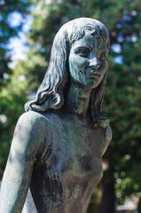 La statua bronzea di una donna dolente su una tomba del cimitero maggiore di Milano