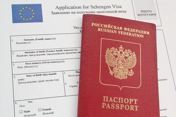 passport and Schengen visa application form in English and Russian language on background. Prohibition and suspension of visas for tourists to travel to European Union and Baltic States concept