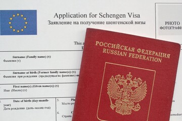 Passport and Schengen visa application form in English and Russian language on background....