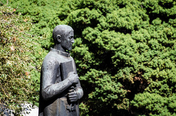 Fototapeta na wymiar Primo piano di una statua bronzea di un uomo che tiene in mano un libro su una tomba del cimitero maggiore di Milano
