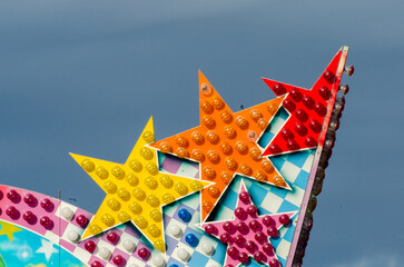 Il dettaglio del tetto di una giostra di un luna park fatto di stelle colorate con dietro un cielo...
