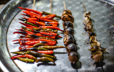 Chili, onion, garlic, skewers, grilled on a charcoal stove, sold for pounding chili paste at the municipal fresh market, Ubon Ratchathani, Thailand,