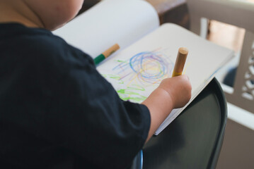 close-up view of toddler using crayons to draw a picture