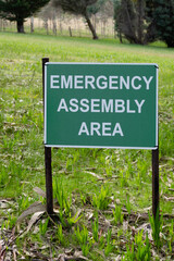 Road sign Emergency Assembly Area plate white on green in the park in Australia