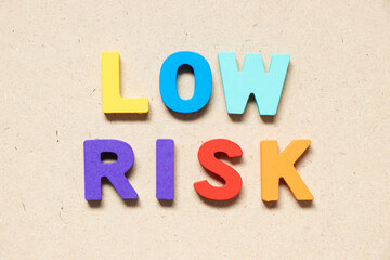 Color alphabet letter in word low risk on wood background