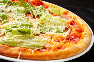 Pizza with salad and cheese in a plate. On a dark background.