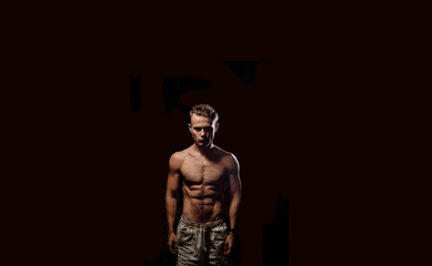 Fototapeta na wymiar sexy athletic man with a naked torso on a dark background