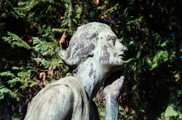 Fototapeta na wymiar Primo piano di una statua bronzea di una donna dolente con un fiore in mano su una tomba del cimitero maggiore di Milano