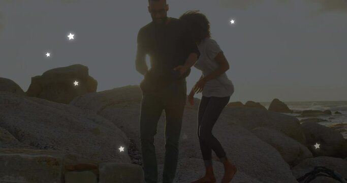 Animation of stars over african american couple at beach