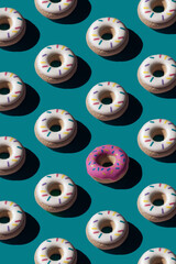 Trendy sunlight seamless pattern made of three colorful doughnut toys with sharp shadow on blue turquoise background. Minimal food summer concept with copy space.