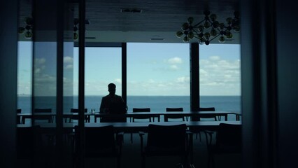 Businessman silhouette working sea view big window. Leader boss thinking