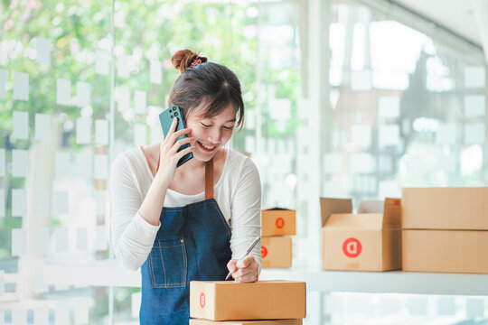 Portrait of a Small Business Startup, SME Owner, Female Entrepreneur work on parcel boxes Receipts and check orders online to prepare boxes. Selling to customers. Online SME business idea.
