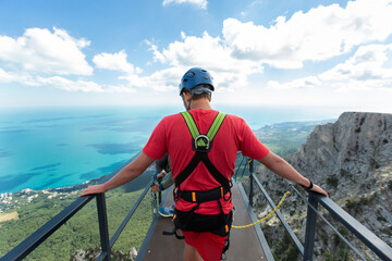 An extreme athlete walks across the bridge to the cliff. Jumping rope.
