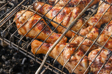 Meat on barbecue grill. Grilled chicken legs or drumsticks. Сooking on the grill in the garden. Shallow depth of field