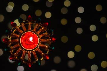 Selective focus on candle of diya lamp lit on dark background with bokeh lights. Diwali festival...