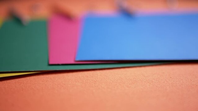 Multicolored Sheets of Cardboard Paper Laid Out on an Orange Table Background. School supplies, pencils, colored paper. Study of colors and shapes. Rainbow, spectrum. Preparing children for school.