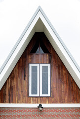 White window with wooden wall on triangular end of roof