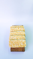 Tempeh in slices on a cutting board, isolated on a white background