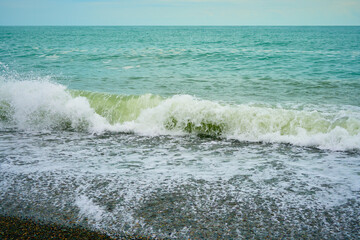 Sea shore with pebbles, wet sea pebbles on the beach and quiet sea surf