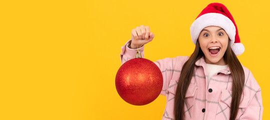 Fototapeta na wymiar Winter child isolated portrait. teen girl with red decorative ball on yellow background. xmas holiday decoration. Banner of christmas child girl, studio kid winter portrait with copy space.