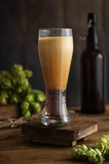 Beer. High foam in a glass after pouring beer. A glass of beer with hops on a vintage wooden board. Beer concept. Oktoborfest. Vintage.