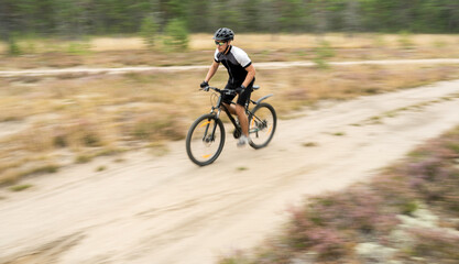 Blurred in motion photo, a man fast on a mountain bike in helmet and gear on the road in the forest eco tourism