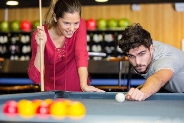 Fototapeta na wymiar young couple playing pool in the bar