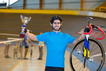 happy young cyclist on a cycle track holding a trophy - obrazy, fototapety, plakaty