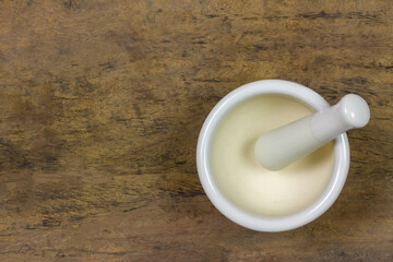 White ceramic mortar and pestle on rustic wooden background, top view.