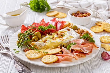 savory baked brie with crackers, salami, nuts, ham