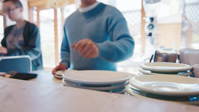Man puts white empty plate on the pile in a cafe