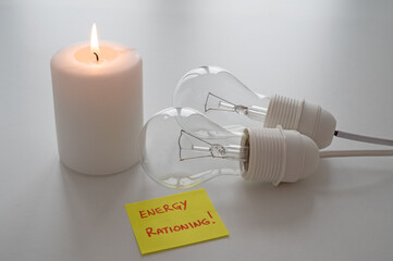 Lit candle, next to two unlit bulbs, with a yellow note with the text 