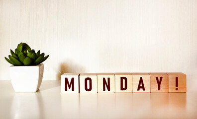 The word MONDAY on wooden cubes and a light table with a flower.