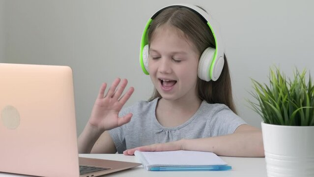 School girl pupil with headphones during online video call on laptop at home
