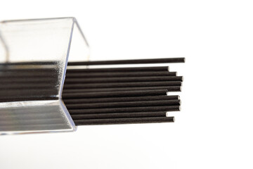 Close up macro shot of a box of pencil lead refill. Black rods of a mechanical pencil in a plastic box